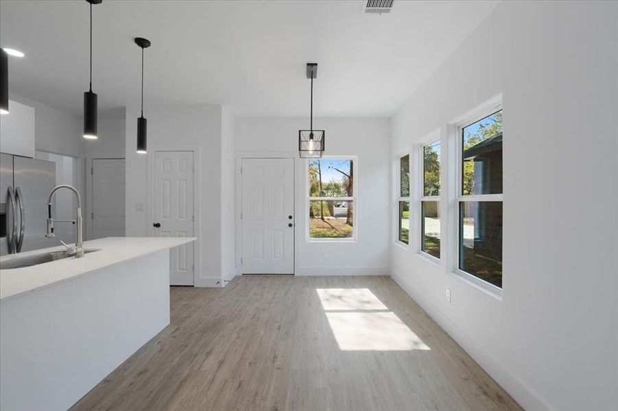 Kitchen with plenty of natural light, decorative light fixtures, and light hardwood / wood-style flooring