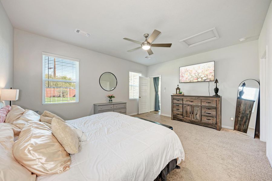 Carpeted bedroom featuring attic access and ceiling fan