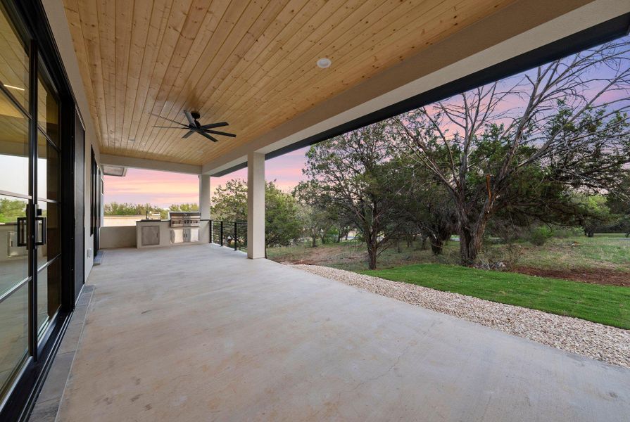 An inviting covered patio features a built-in outdoor kitchen, ideal for al fresco dining and entertaining.