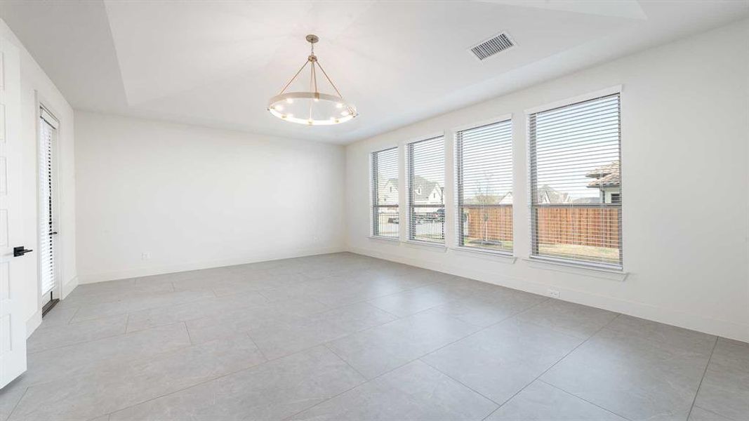 Empty room with an inviting chandelier, a wealth of natural light, and light tile patterned flooring