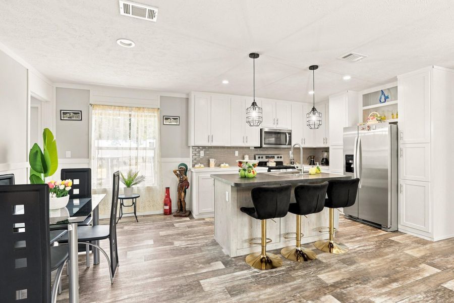 Recessed lighting highlights the contemporary kitchen fitted with an island and wood-look flooring.