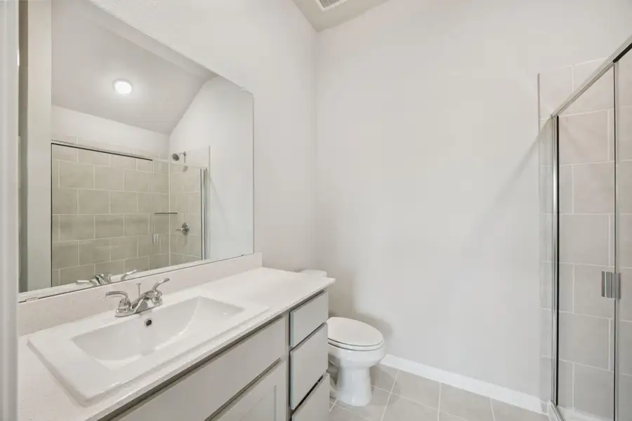 Full bath featuring vanity, a tile shower, and tile patterned floors