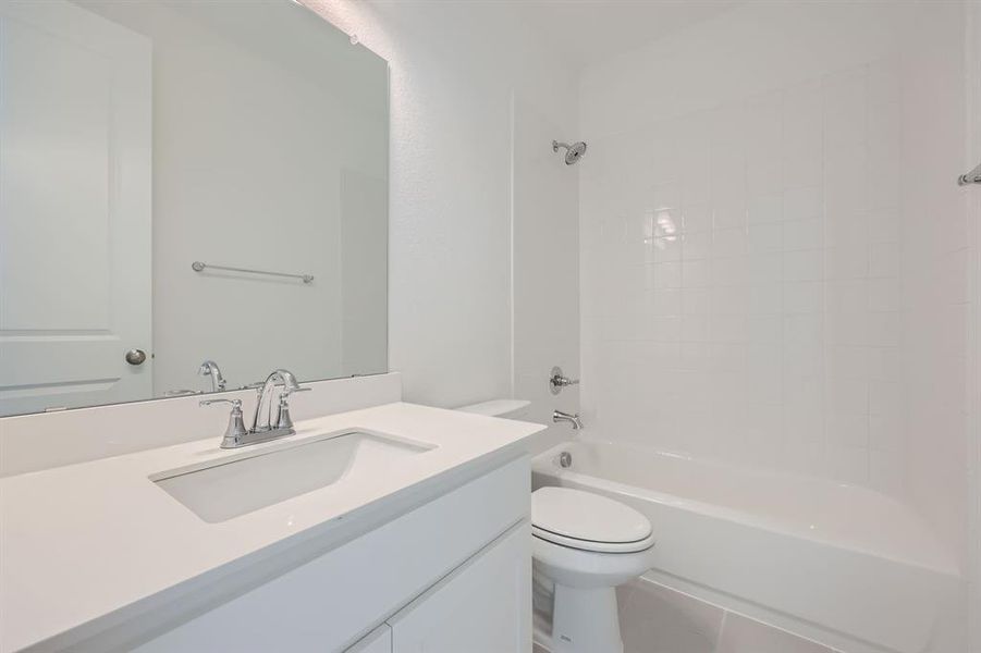 Full bathroom with toilet, tiled shower / bath, vanity, and tile patterned flooring