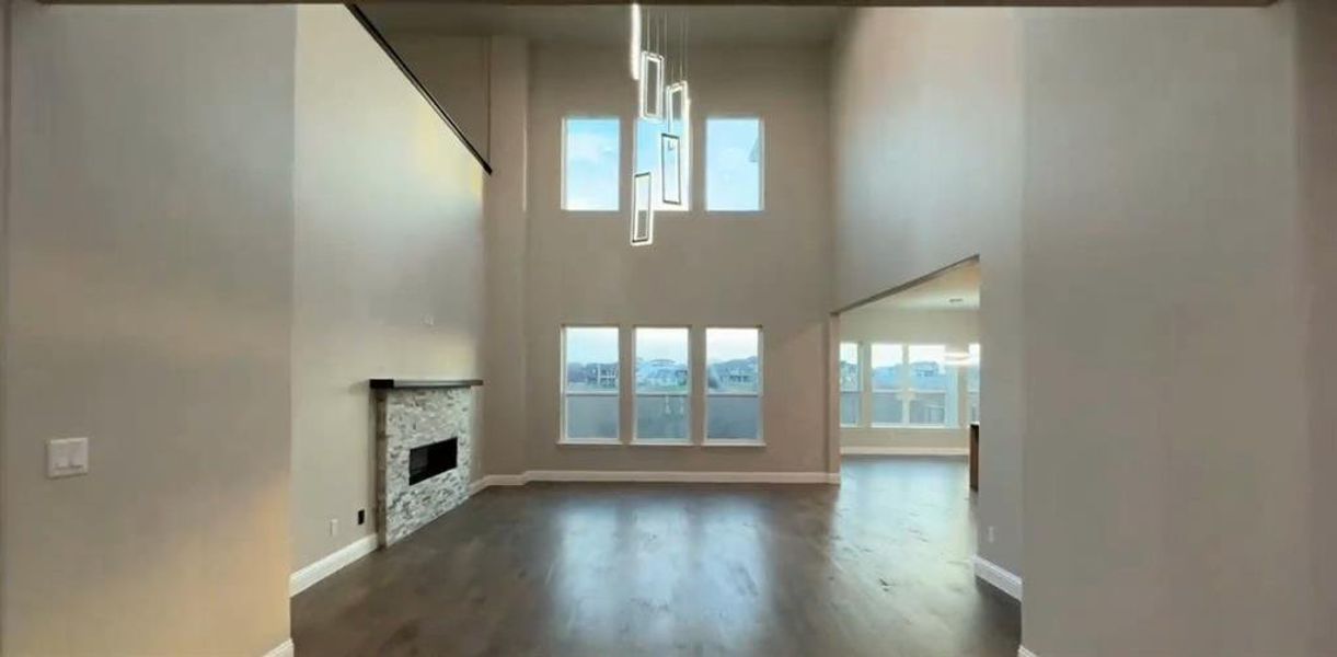 Soaring Ceilings spacious living room featuring healthy amount of natural light, a fireplace, dark wood-type flooring, and a high ceiling