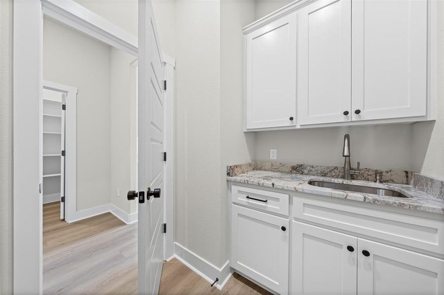 Bar featuring white cabinets, light stone counters, and light wood-style floors