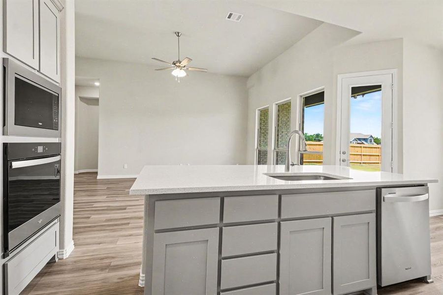 Kitchen island with a built-in sink, stainless steel dishwasher, and light-toned countertop Kitchen island with a built-in sink, stainless steel dishwasher, and light-toned countertop