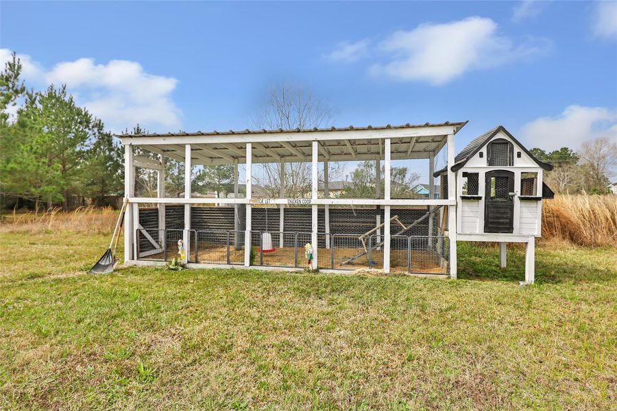 Charming outdoor chicken coop with a covered area and adjacent fenced run, set in a spacious grassy yard. Ideal for homesteaders or those interested in raising chickens.