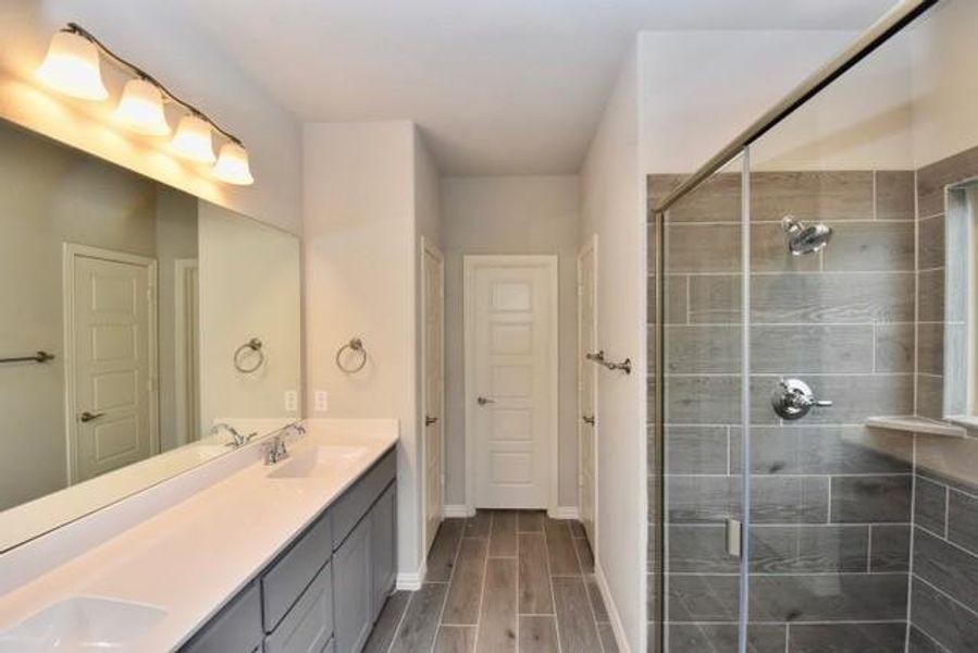 Double vanity, a walk-in shower, and tile flooring