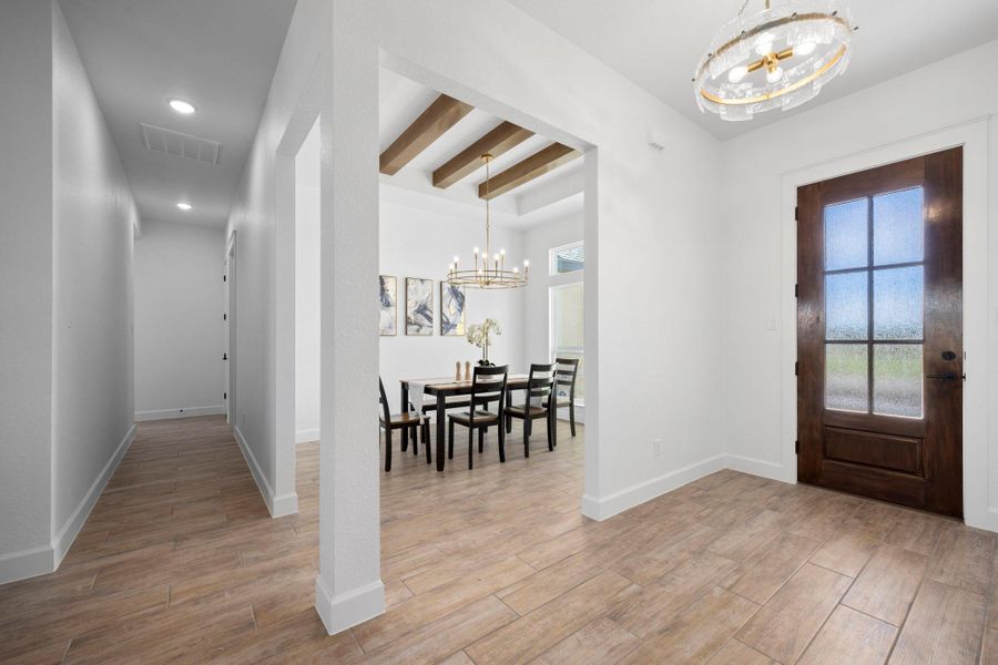 Foyer entrance with a chandelier, light wood-style flooring, beamed ceiling, and healthy amount of natural light