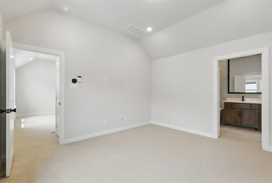Unfurnished bedroom featuring vaulted ceiling, light carpet, recessed lighting, and connected bathroom
