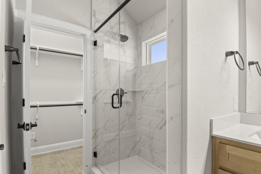 Image of primary bathroom with a marble tiled walk-in shower with a window and a connecting walk-in closet Image of primary bathroom with a marble tiled walk-in shower with a window and a connecting walk-in closet