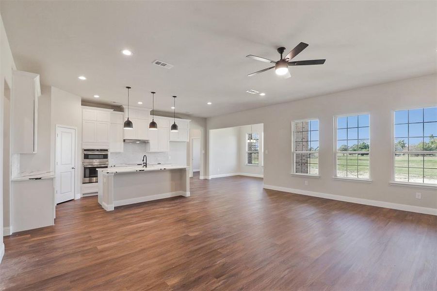 Unfurnished living room with ceiling fan, sink, and dark hardwood / wood-style floors