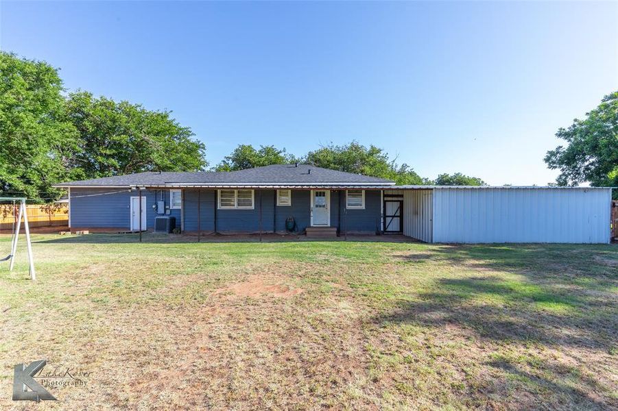 Back of property featuring a yard and roof with shingles