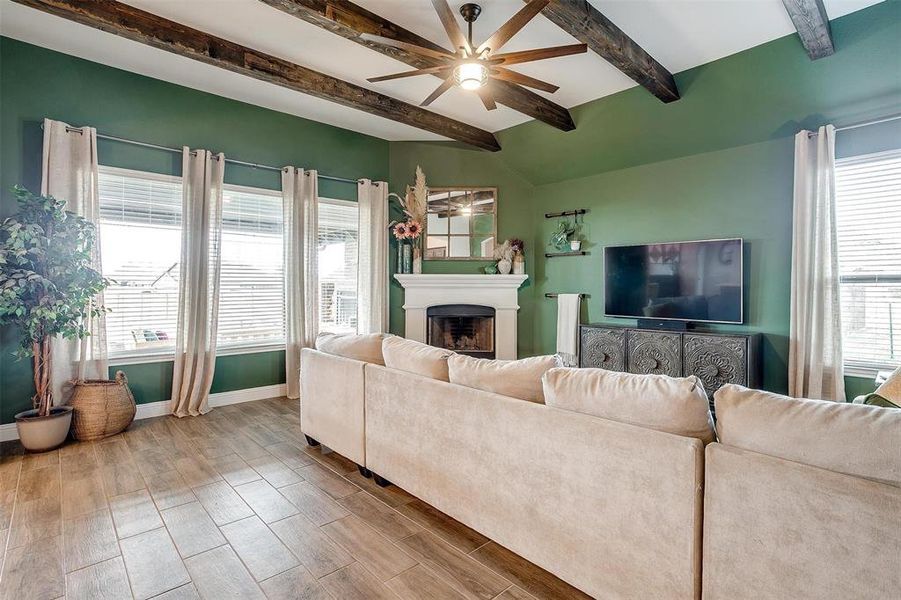 Living room featuring beamed ceiling, wood-type flooring, plenty of natural light, and ceiling fan