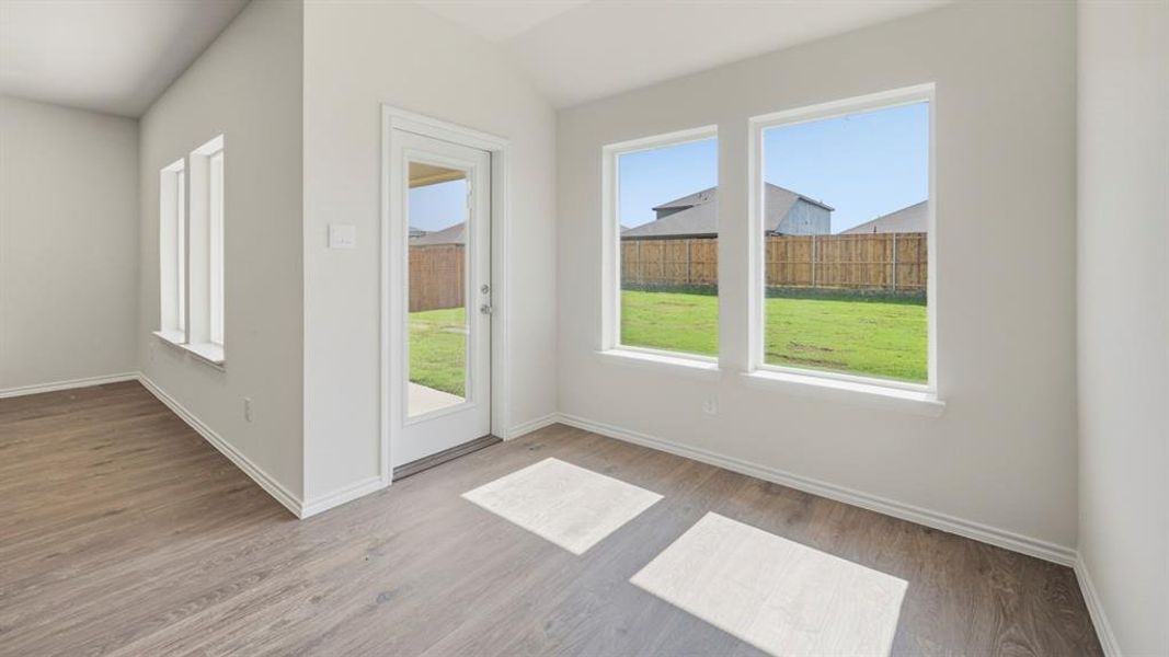 Spare room featuring wood finished floors and lofted ceiling
