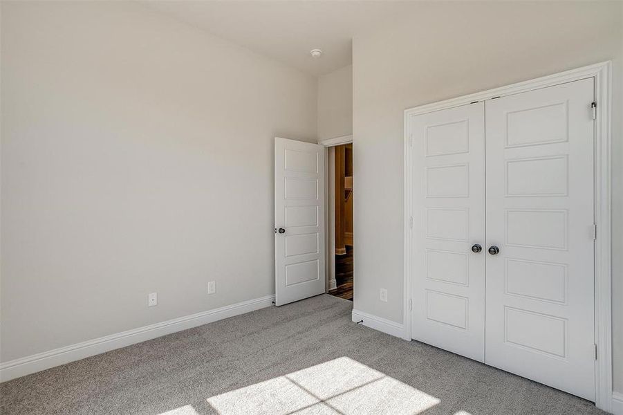 Unfurnished bedroom with light carpet and a closet