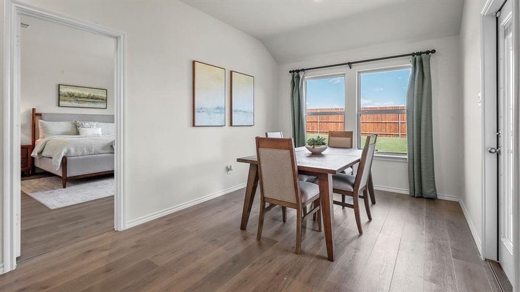 This room features wood flooring, neutral tone walls, and two windows with views of the fenced yard