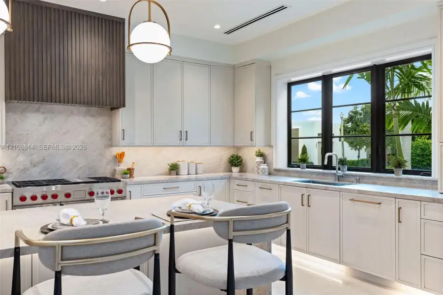 Kitchen featuring flat-panel cabinetry, a stone-surfaced island and countertops, a custom slatted wood range hood, a professional-style gas range, and large-format windows with black frames Kitchen featuring flat-panel cabinetry, a stone-surfaced island and countertops, a custom slatted wood range hood, a professional-style gas range, and large-format windows with black frames