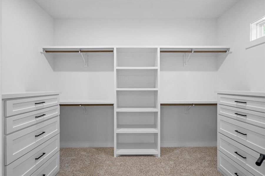 Walk in closet featuring light carpet, built in dressers, and custom closet Walk in closet featuring light carpet, built in dressers, and custom closet