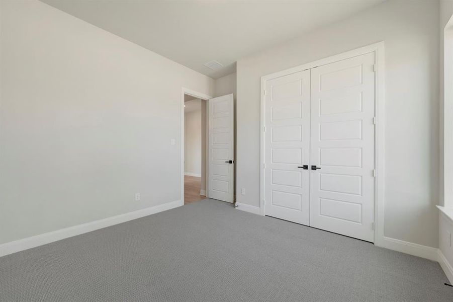 Unfurnished bedroom with light carpet and a closet