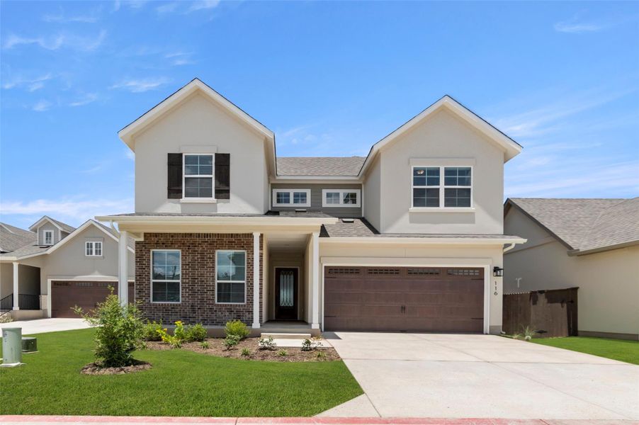 Traditional home featuring driveway, brick siding, an attached garage, a front yard, and stucco siding Traditional home featuring driveway, brick siding, an attached garage, a front yard, and stucco siding