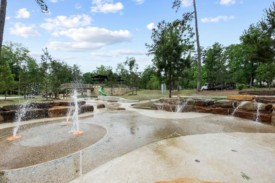The community's extensive amenities include a modern splash pad and water feature area, perfect for cooling off during the summer months. Surrounded by mature trees and natural stone accents, this park-like setting provides endless outdoor entertainment for residents.