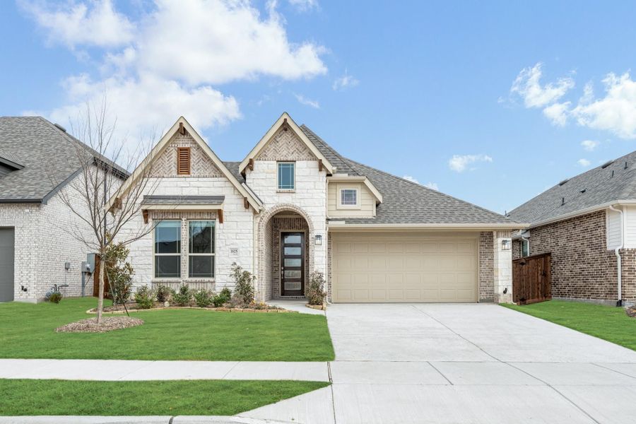 Single-story home with white stone exterior, arched entry, two-car garage, and green front lawn Single-story home with white stone exterior, arched entry, two-car garage, and green front lawn