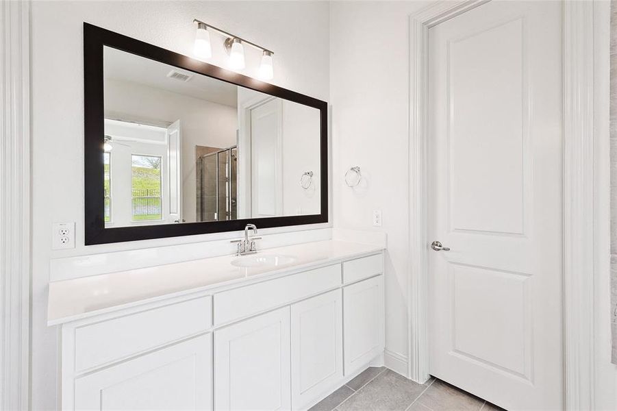 Bathroom featuring a shower with shower door, vanity, and tile floors