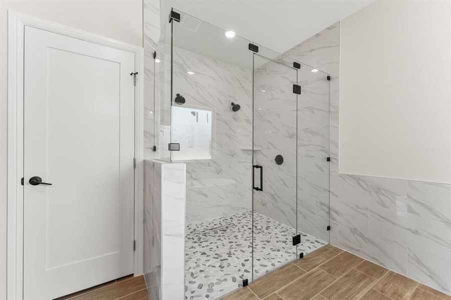 Bathroom with tile walls, a marble finish shower, and wood tiled floors