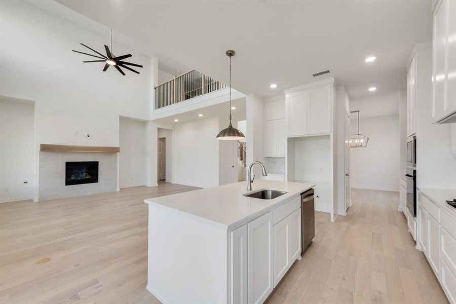 Kitchen featuring white cabinetry, light wood-style flooring, open floor plan, an island with sink, and recessed lighting Kitchen featuring white cabinetry, light wood-style flooring, open floor plan, an island with sink, and recessed lighting