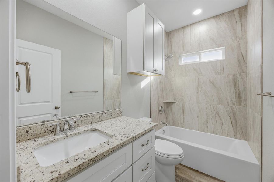 A well-appointed bathroom features a spacious vanity with a broad mirror and a tiled shower with a soaking tub.