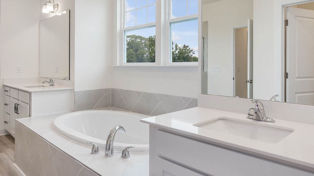 Stonehaven home plan primary bathroom with separate vanities, soaking tub, linen closet and tile shower Stonehaven home plan primary bathroom with separate vanities, soaking tub, linen closet and tile shower