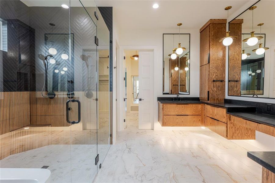 Bathroom featuring double vanity, a stall shower, light marble finish flooring, and recessed lighting