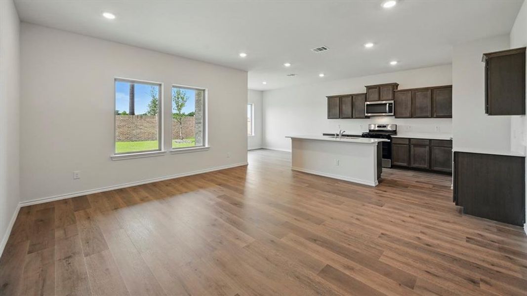 Kitchen with open floor plan, recessed lighting, appliances with stainless steel finishes, a kitchen island with sink, and dark wood finished floors
