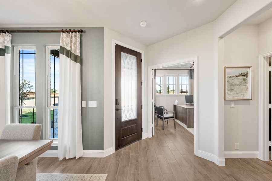 Entryway with dark wood front door, glass panel, wood-look floors, and view into home office