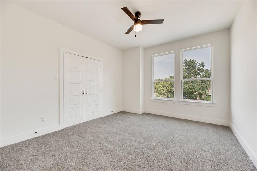 Unfurnished bedroom featuring light carpet, ceiling fan, and a closet