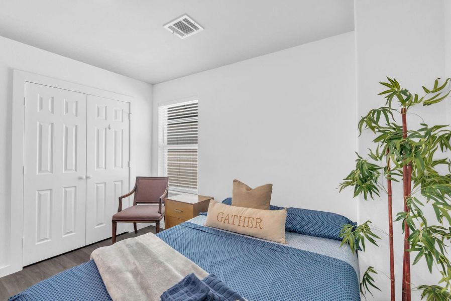 This adorable bedroom featuring a double closet, natural light from a window, a comfortable bed with decorative pillows, a wooden chair, and a potted plant for a touch of greenery. Currently used as an Airbnb Room with full bathroom off the landing. This adorable bedroom featuring a double closet, natural light from a window, a comfortable bed with decorative pillows, a wooden chair, and a potted plant for a touch of greenery. Currently used as an Airbnb Room with full bathroom off the landing.