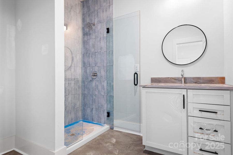 Private ensuite bath in upper guest bedroom offers a walk-in tile shower, white vanity and plenty of room.