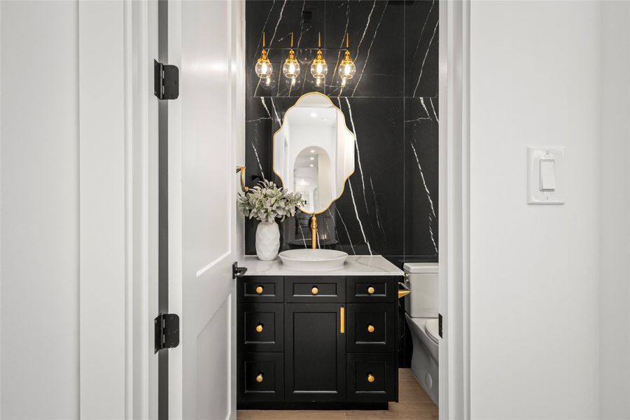 Designer powder bath on the main level with high-end custom cabinetry, quartz countertops, a vessel sink, and brushed-gold hardware. Designer powder bath on the main level with high-end custom cabinetry, quartz countertops, a vessel sink, and brushed-gold hardware.