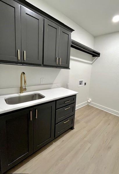 Washroom featuring hookup for a washing machine, cabinet space, light wood finished floors, and hookup for an electric dryer