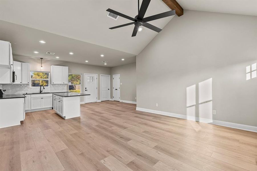 Kitchen featuring open floor plan, white cabinetry, a kitchen island, light wood finished floors, and beamed ceiling Kitchen featuring open floor plan, white cabinetry, a kitchen island, light wood finished floors, and beamed ceiling