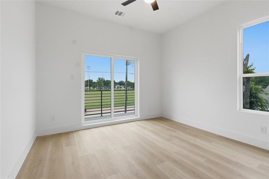 Bright room with light wood-finish flooring, white walls, and a ceiling fan Bright room with light wood-finish flooring, white walls, and a ceiling fan