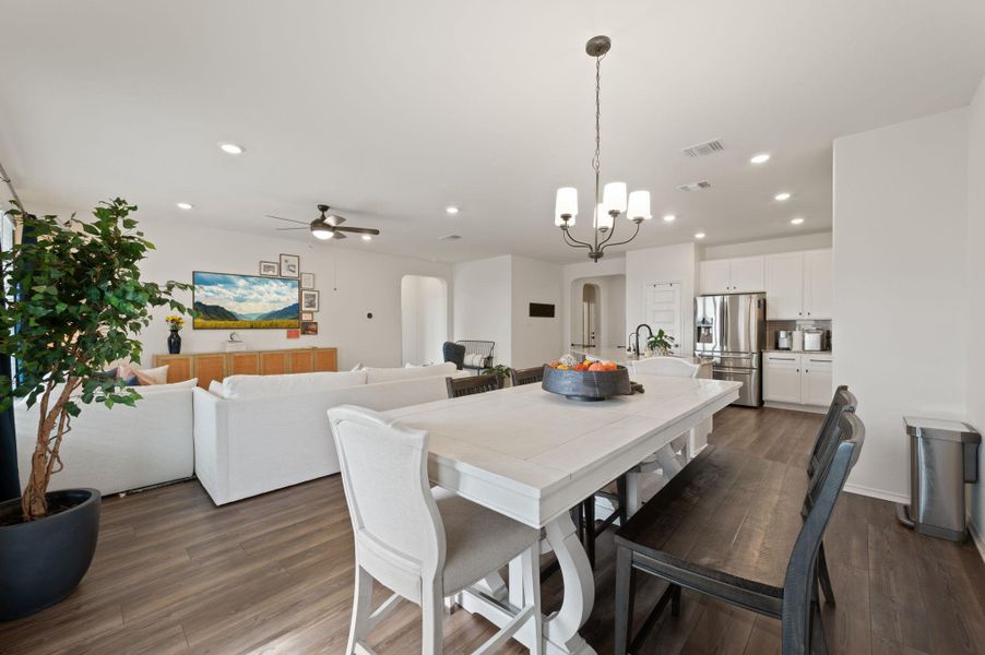 Dining space featuring arched walkways, suspended lighting, dark wood-style floors, and ceiling fan