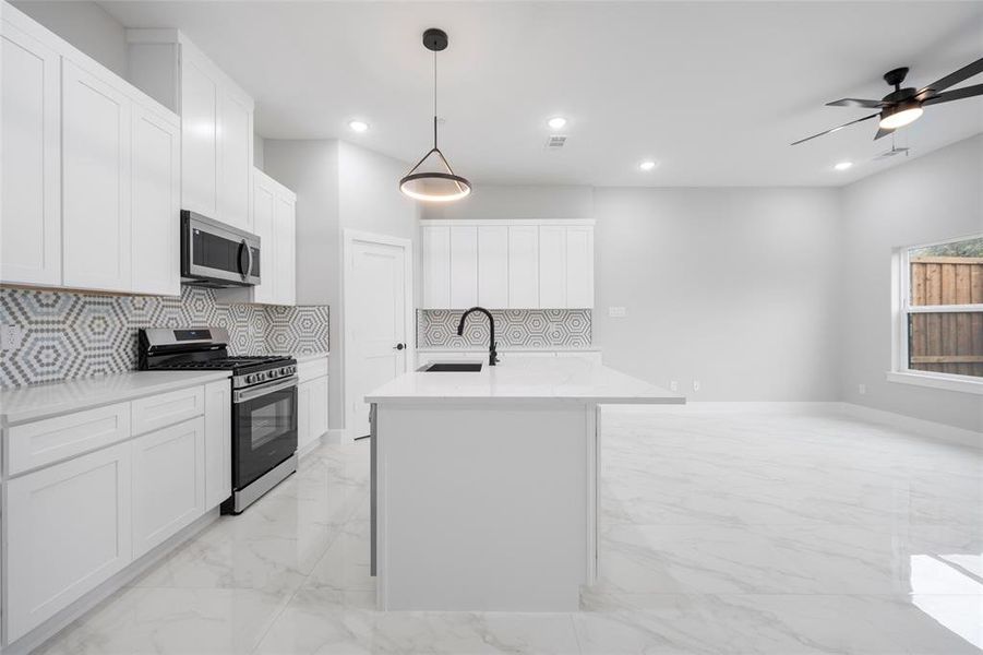 Kitchen with recessed lighting, stainless steel appliances, marble finish floor, white cabinetry, and a sink