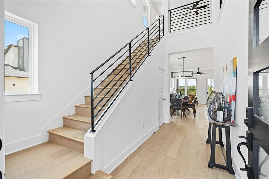Dramatic high ceiling entrance with view to back exterior,  the contemporary  horizontal black railing leads to second level
