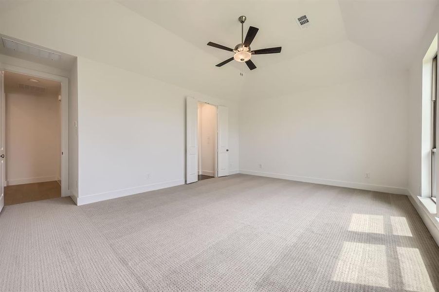 Spare room featuring light carpet, ceiling fan, lofted ceiling, and baseboards