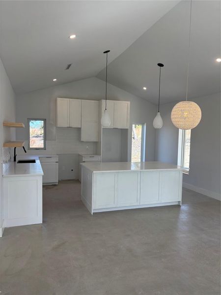 Kitchen featuring white cabinetry, backsplash, decorative light fixtures, a kitchen island, and sink