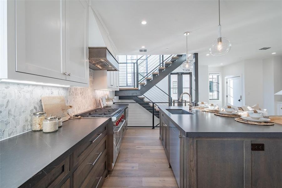 Kitchen with appliances with stainless steel finishes, dark brown cabinets, sink, pendant lighting, and white cabinetry