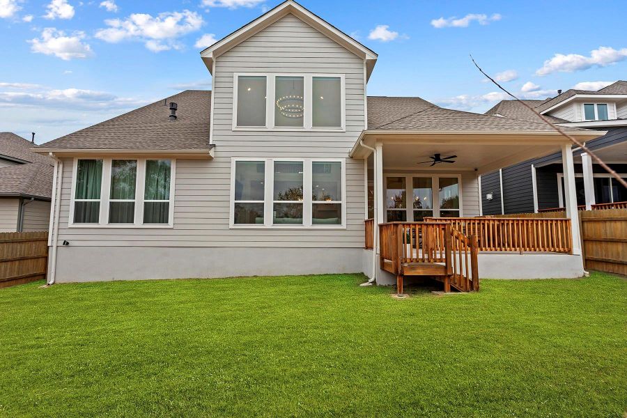 Back of property with ceiling fan and a lawn