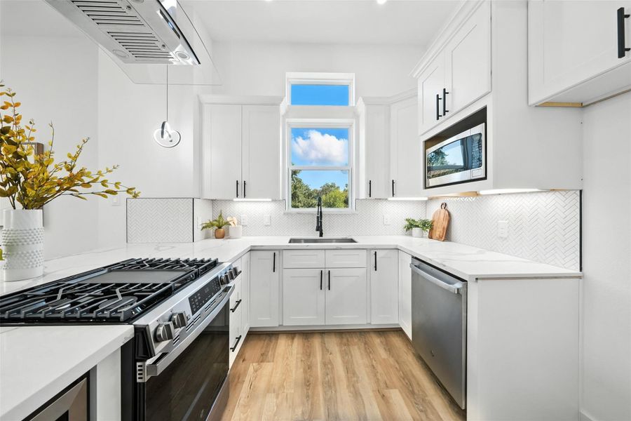 Designer kitchen with a clean, modern aesthetic, featuring Quartz countertops, custom cabinetry, under-cabinet lighting, and a herringbone tile backsplash. Equipped with stainless steel appliances, gas range, and ample prep space, this bright layout combines style and functionality for everyday living. Designer kitchen with a clean, modern aesthetic, featuring Quartz countertops, custom cabinetry, under-cabinet lighting, and a herringbone tile backsplash. Equipped with stainless steel appliances, gas range, and ample prep space, this bright layout combines style and functionality for everyday living.